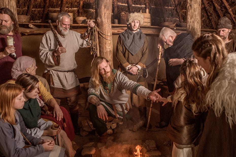 Des Vikings (hommes, femmes et enfants) réunis sous une tente au cours d'un rituel religieux